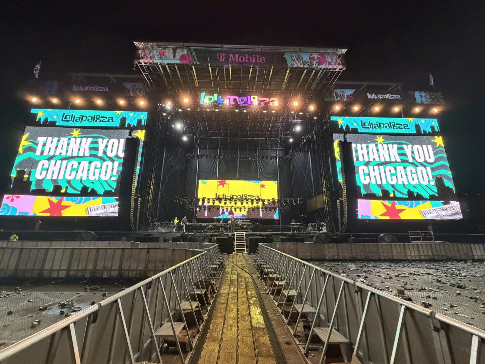 Lollapalooza stage at night with colorful Thank You Chicago screens and a central aisle between crowd barriers.
