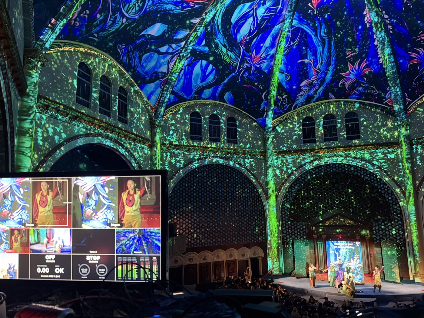 Blue and green imagery projected across an ornate vaulted interior.