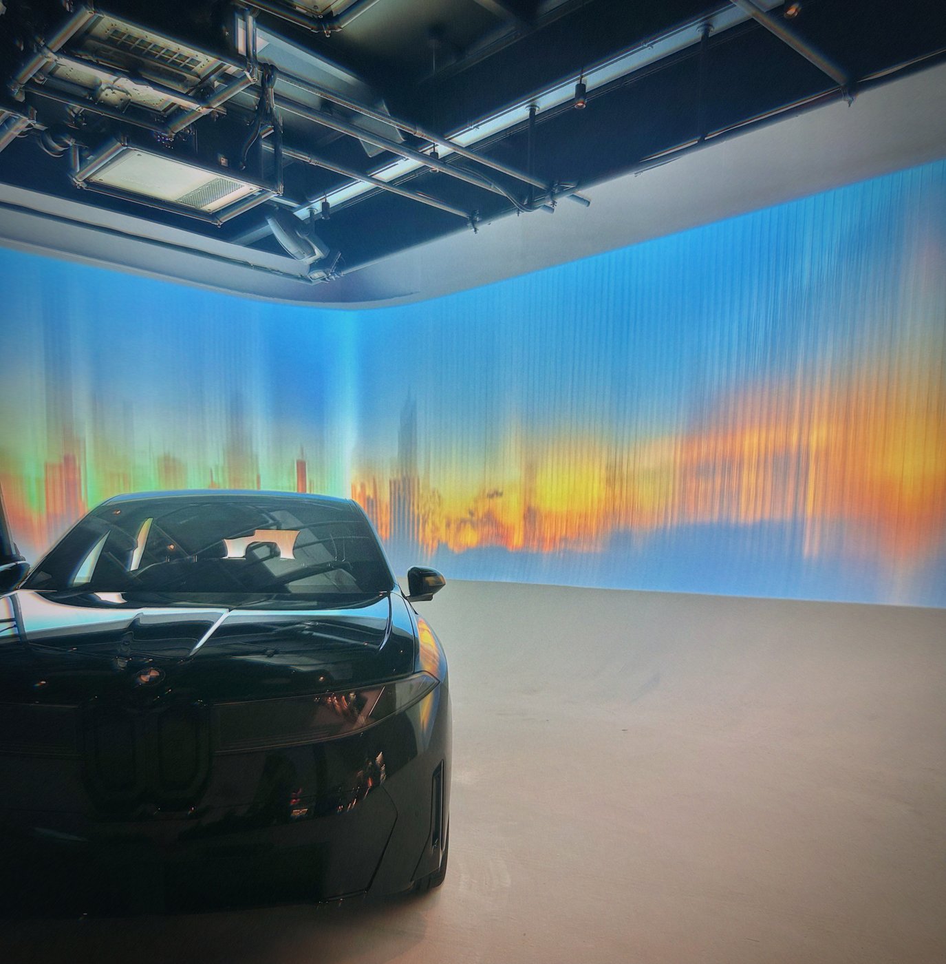 A black car inside a room surrounded by a panoramic blue and orange landscape.